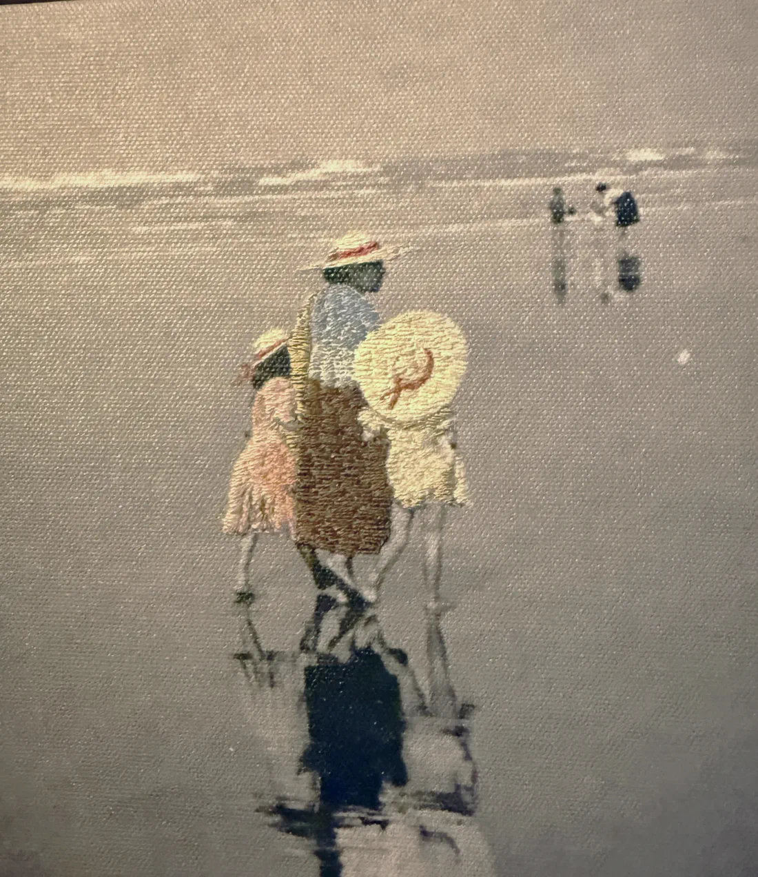 A stitched canvas of three figures in straw hats walking away across wet sand, their reflections beneath them.
